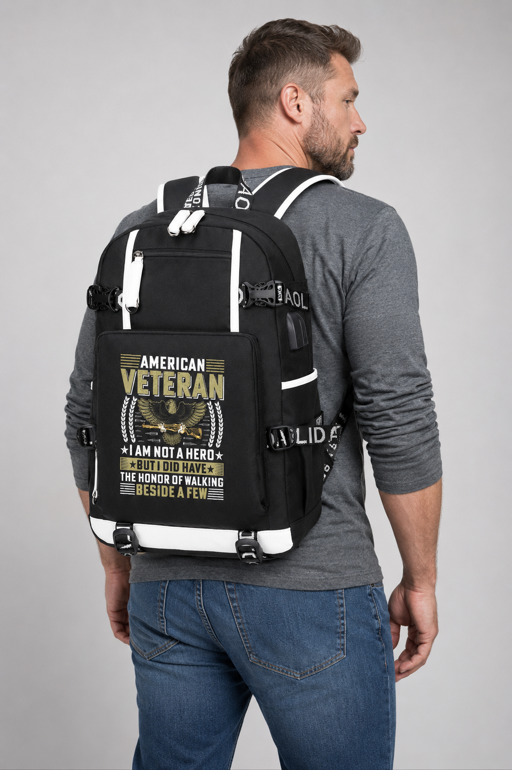 Adult model wearing American Veteran I Am Not a Hero black backpack, three-quarter rear view