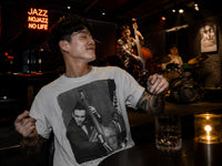 Thumbnail for Man wearing the white Charles Mingus jazz portrait T-shirt at a live jazz club with an upright bassist and drummer